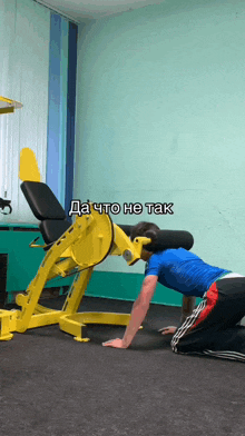 a man in a blue shirt is doing push ups on a yellow machine with a caption in russian that says da to he tak