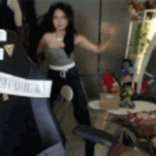 a woman is dancing in front of a computer monitor in a room .