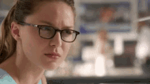 a woman wearing glasses is making a funny face in a room .