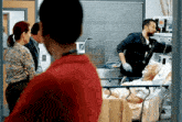 a man in a red shirt is looking at an elderly man in a hospital bed .