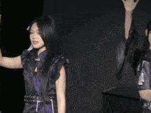a woman in a purple and black outfit holds her hand up