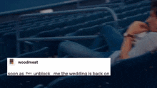 a man is sitting in a stadium watching a baseball game with a message .