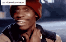 a man wearing a red beanie is smiling with a box video downloader sticker behind him