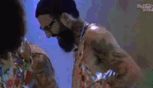 a man with a beard and glasses is standing next to a woman in a colorful shirt .