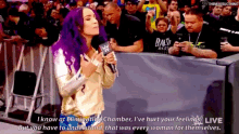 a woman with purple hair is speaking into a microphone while standing in front of a crowd