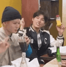 a group of young men are sitting at a table eating food and drinking juice .