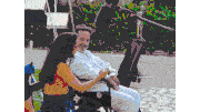 a woman sits next to a man in a wheelchair with a cat