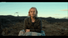 a woman sits in a field with bbc written on the bottom right
