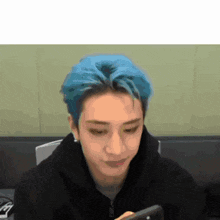 a man with blue hair is holding a cell phone .