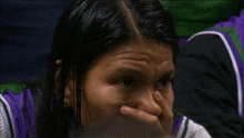 a woman covering her mouth with her hand in front of a pink sign that says 16