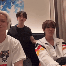 a man wearing a tom and jerry t-shirt sits next to two other people