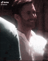 a man in a white shirt is smiling with his eyes closed in a tik tok video