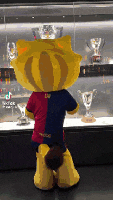 a mascot is standing in front of a glass display of trophies .