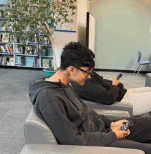 a man sits in a chair looking at his cell phone