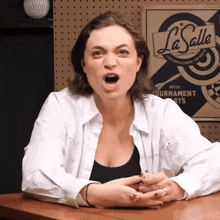 a woman sitting at a table with her mouth open in front of a la salle sign