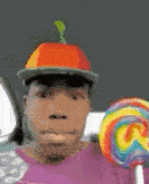 a man wearing a hat and holding a rainbow lollipop .