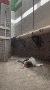 a man is laying in the rain under a pipe with a warning sign on it