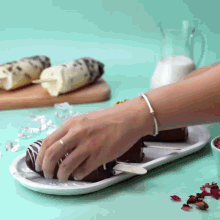 a person with a bracelet on their wrist is putting ice cream on a stick on a white plate