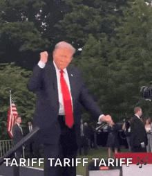 a man in a suit and tie is dancing with the words tariff tariff tariff written on the bottom .