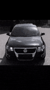 a black car is parked in front of a building with mountains in the background