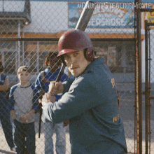 a man holding a baseball bat in front of a fence with a sign that says ' caught stealing movie '
