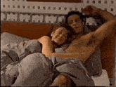 a man and a woman are laying in bed with the man 's shirt off