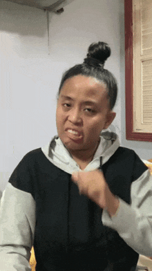 a woman with her hair in a bun is making a funny face .