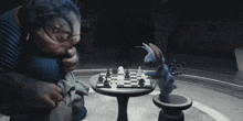 a man and a stuffed animal are playing chess on a small table