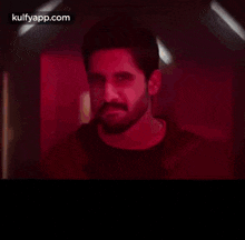 a man with a beard is wearing a red shirt and a black shirt and says bandaina .