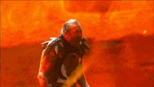 a man with red paint on his face is standing in front of flames