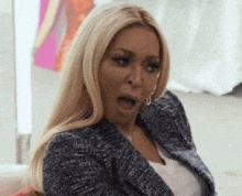 a woman is sitting on a couch with her mouth open and a surprised look on her face .