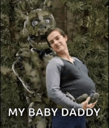 a pregnant man is standing next to a costume of a springtrap .