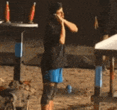 a man in a black shirt and blue shorts is talking on his cell phone