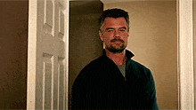 a man with a beard is standing in a hallway looking at the camera .