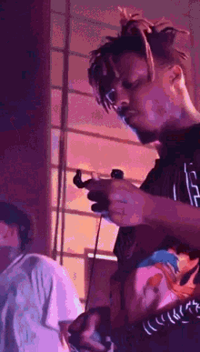 a man with dreadlocks is holding a video game controller in his hand