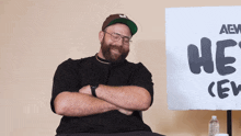 a man sitting in front of a sign that says " he 's "