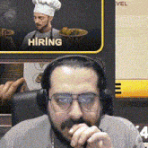 a man wearing headphones is sitting in front of a screen that says hiring