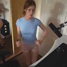 a woman in a blue shirt and pink shorts is standing next to a microphone