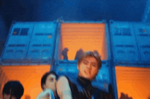 a group of people are dancing in front of a building with containers .