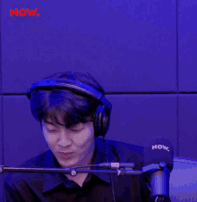 a man wearing headphones stands in front of a microphone that says now on it