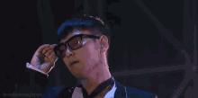 a man in a tuxedo and tie is smoking a cigarette with the words hourlyseunghyun below him