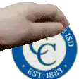 a hand is holding a blue and white circle that says ' est 1883 ' on it