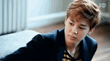 a young man in a suit is laying on a bed .