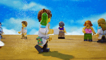 a group of lego figures standing on a beach