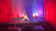 a person doing a handstand on a stage with purple and blue lights behind them