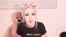 a woman is talking to a teddy bear in front of a window .