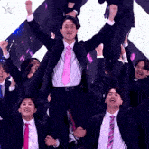 a man in a suit and pink tie is being lifted in the air