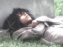 a man in a suit is laying in the grass with his eyes closed