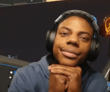 a young man wearing headphones and a blue hoodie is smiling .