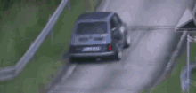 a blue car is driving down a hill on a track .
